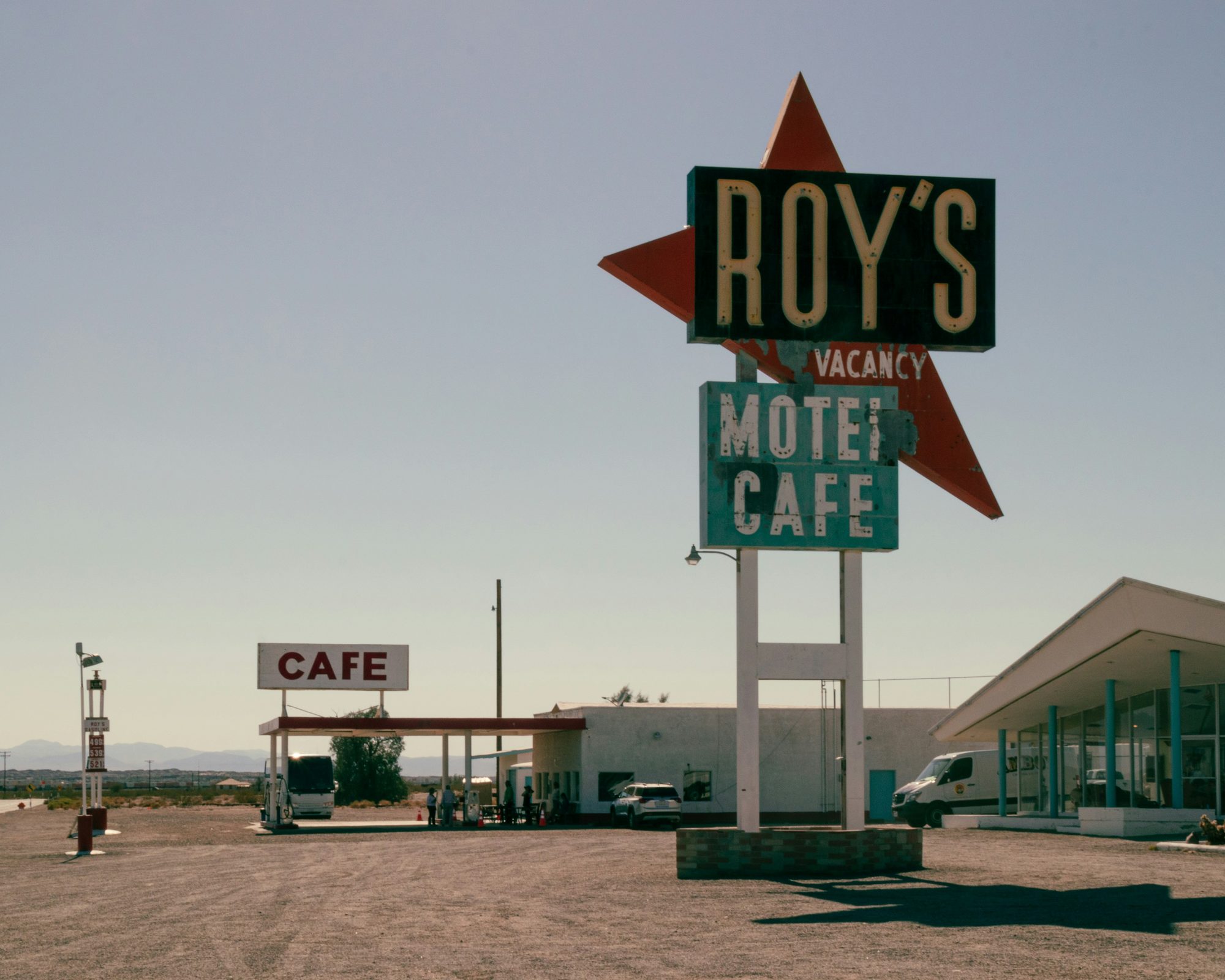 A retro desert motel and cafe sign under a pale sky