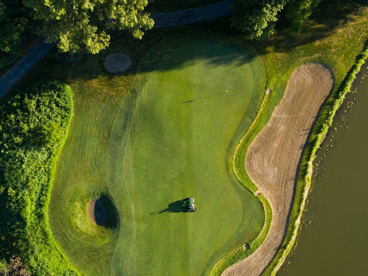 Aerial view of a green with a bunker beside a dark water hazard