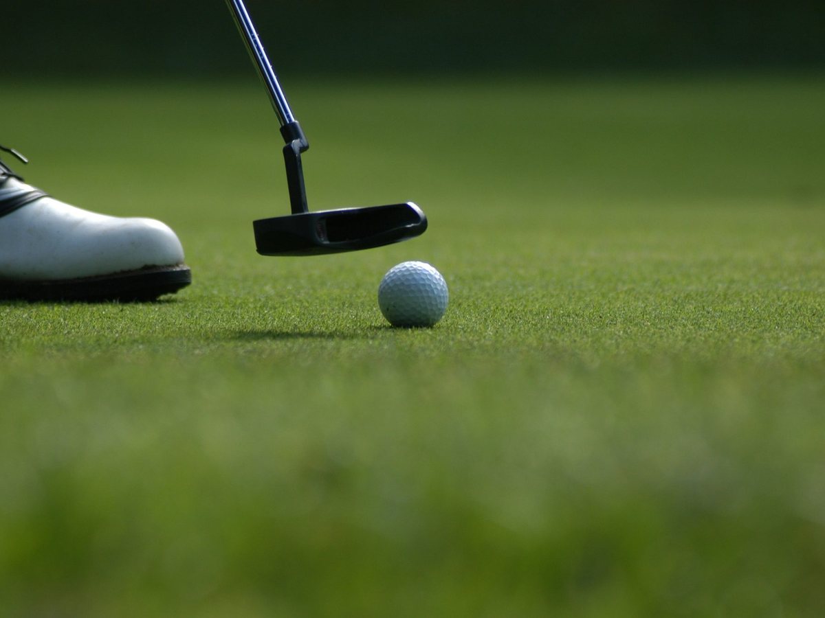 A putter and ball on a dewy green