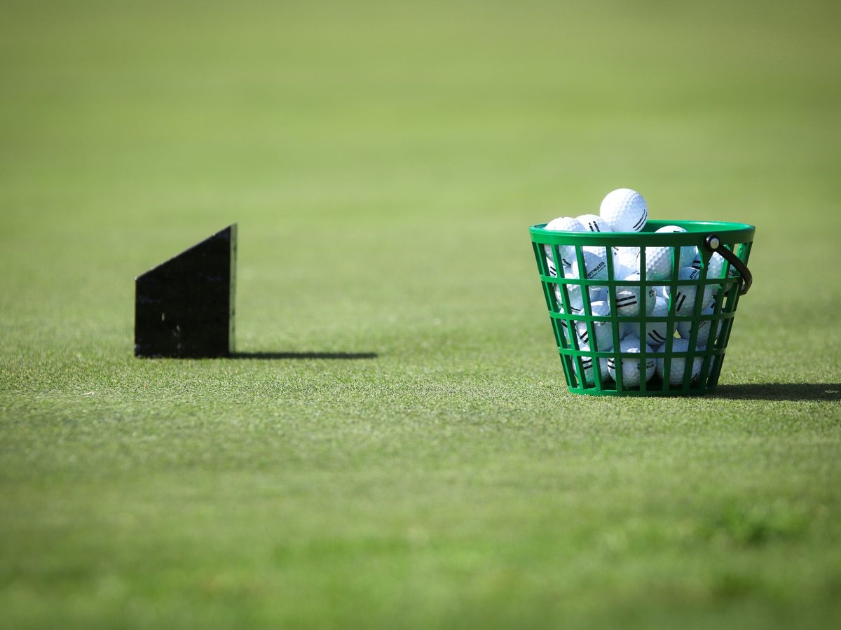 A basket of range balls beside a tee marker